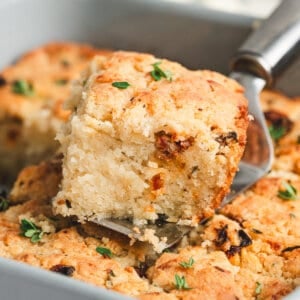 A Marry Me butter swim biscuit being lifted from a baking dish on a spatula.