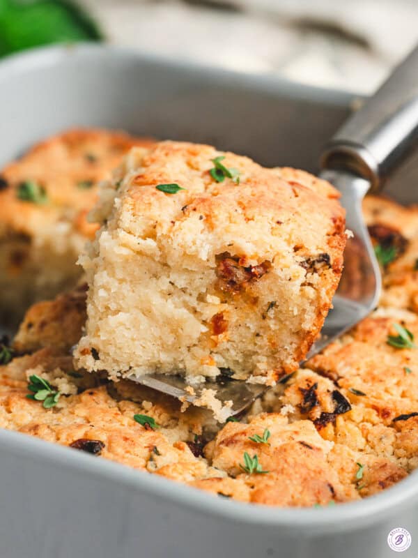 A Marry Me butter swim biscuit being lifted from a baking dish on a spatula.